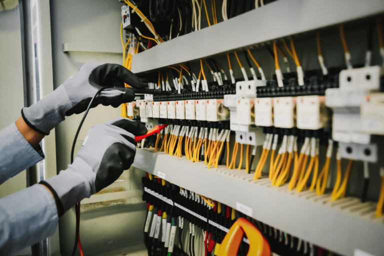 A person in gloves is working on a panel during a commercial electrical survey.